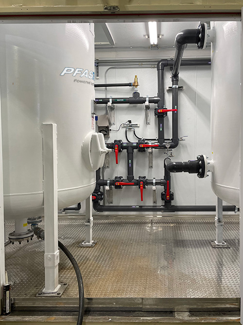 Interior view of PRM containerized water treatment enclosure with control panel and piping systems