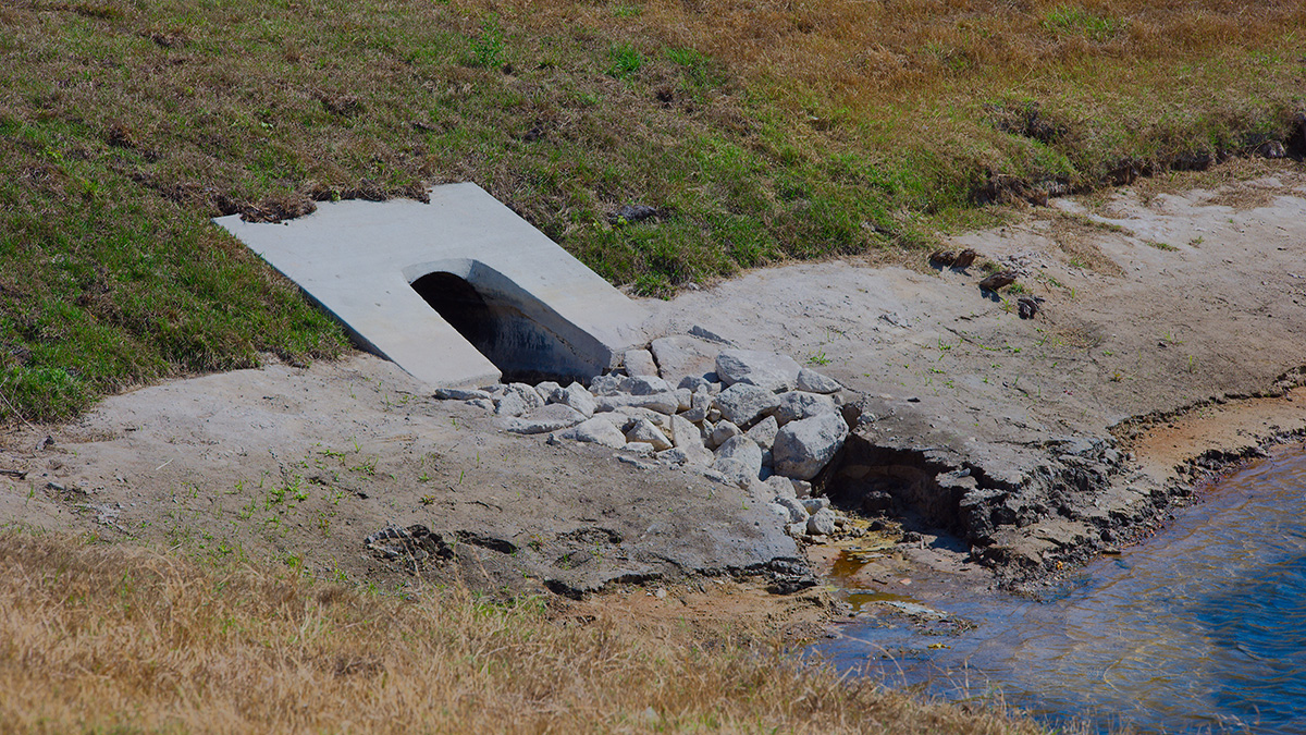 Concrete culvert outlet structure and rip-rap energy dissipator at a dry-climate stormwater retention basin — conventional retention ponds accumulate PFAS through evaporative concentration and transform precursor compounds into terminal PFAS during long hydraulic residence times